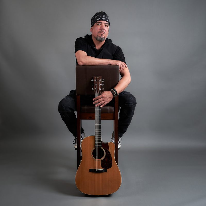 Sammy Vélez seated with an acoustic guitar